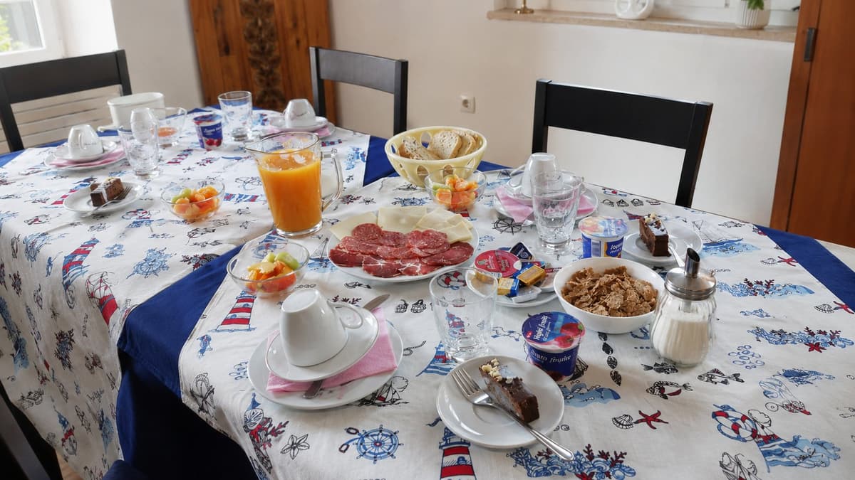 Breakfast laid on a table — cold cuts, cheese, fruit, coffee and fresh orange juice