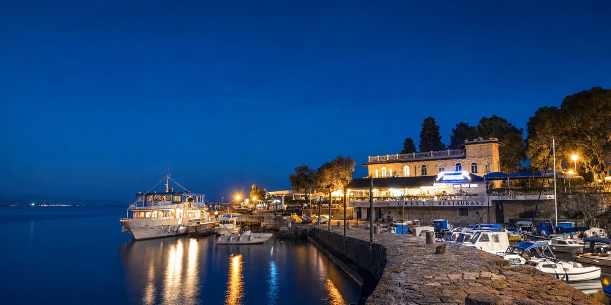 Lovran harbour at blue hour, boats moored under the shore lights