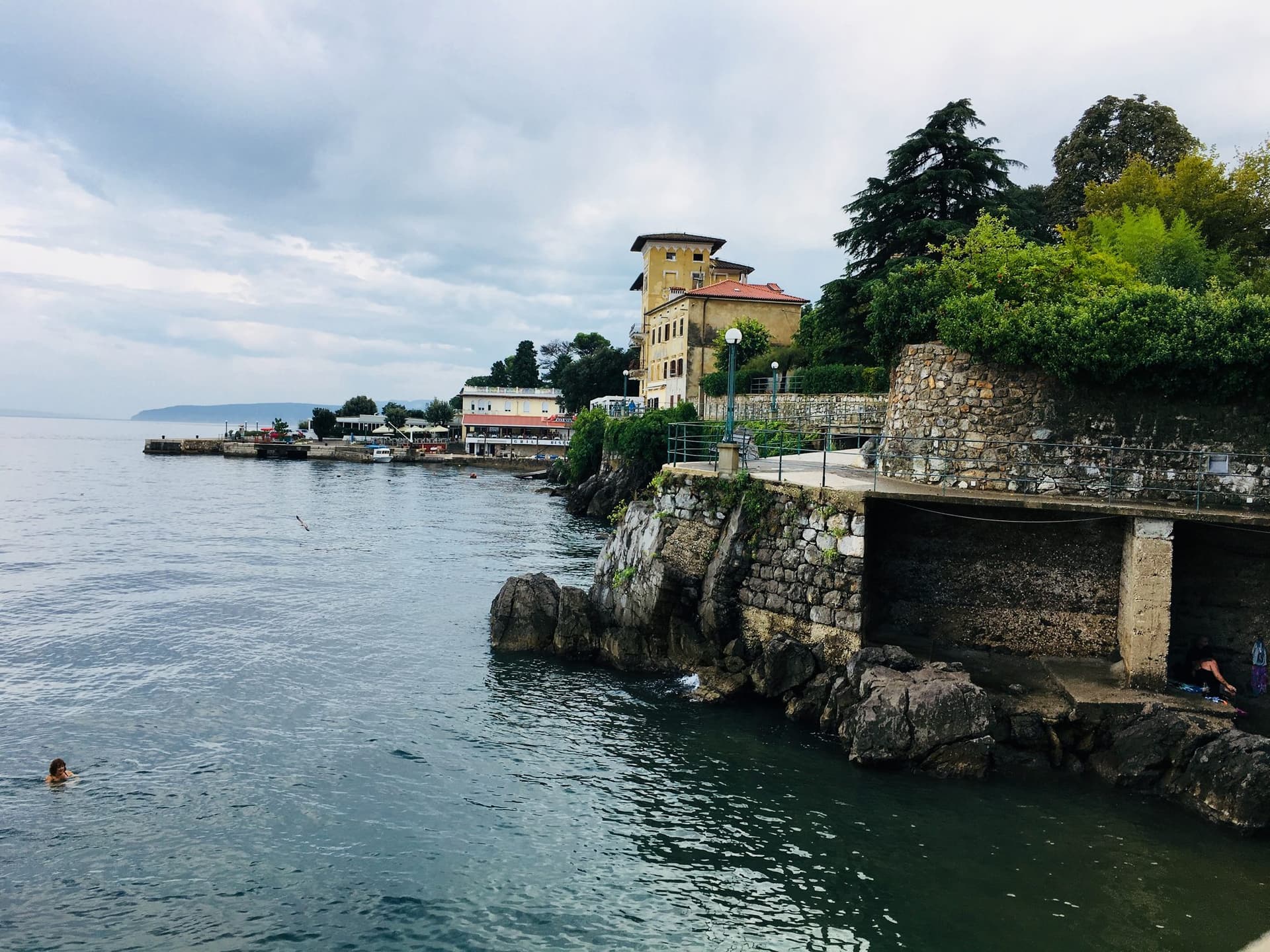 A rocky swimming cove on the Lungomare, with the old tower above it